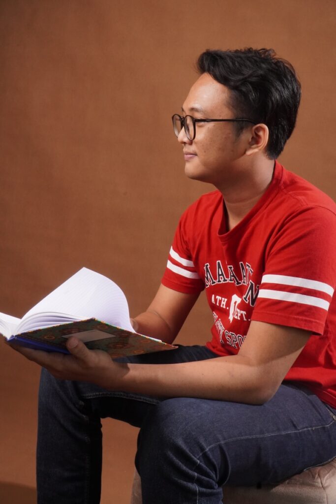 a man sitting on a stool reading a book